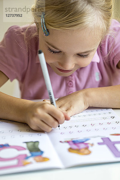 Smiling little girl writing numbers in exercise book
