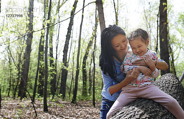 Mother and daughter in park  sitting on tree trunk