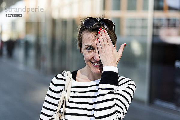 Portrait of smiling woman covering eye with her hand