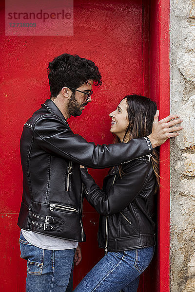 Happy young couple standing at red door