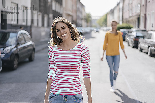 Woman walking in street  followed by friend