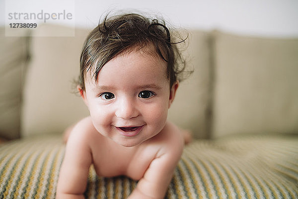Portrait of smiling baby girl lying on couch