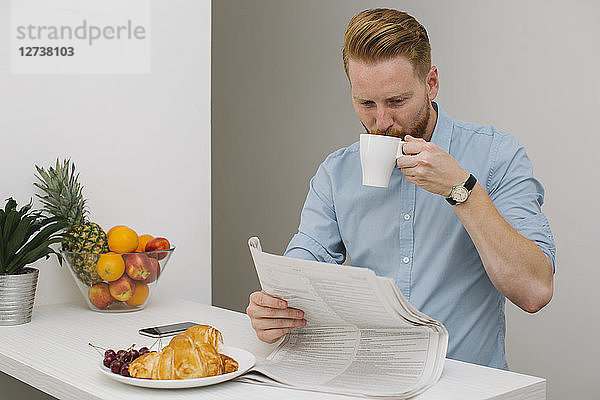 Businessman drinking coffee while reading newspaper in the morning at home