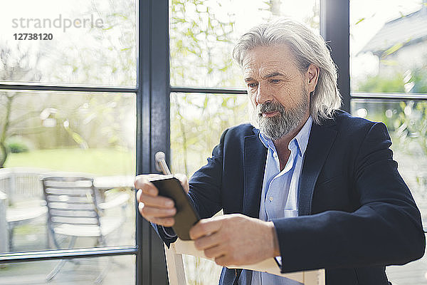 Senior businessman sitting on chair  using smartphone