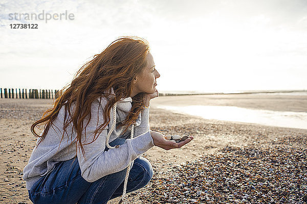 Redheaded woman collecting shell on the beach