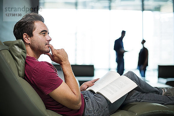Man in office sitting in armchair  reading a book