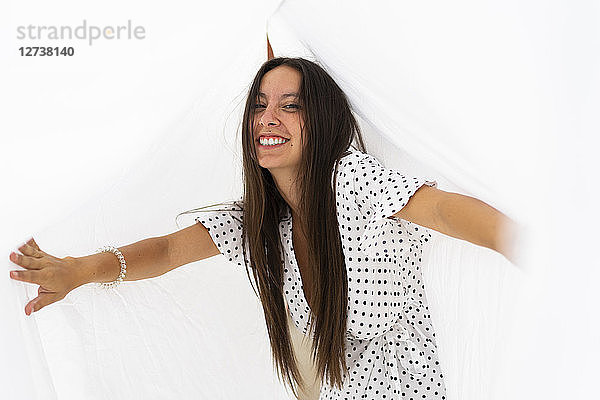 Portrait of young woman having fun with drying bed sheets on roof terrace
