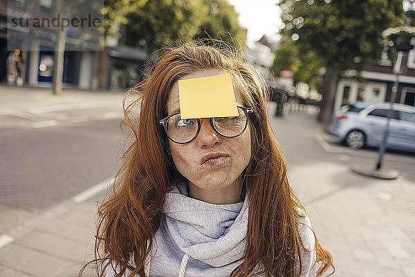 Redheaded woman with adhesive note sticking on her forehead
