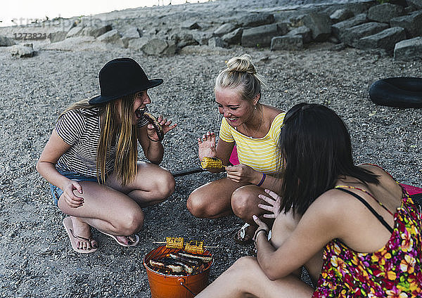 Three young women sitting together having a barbecue