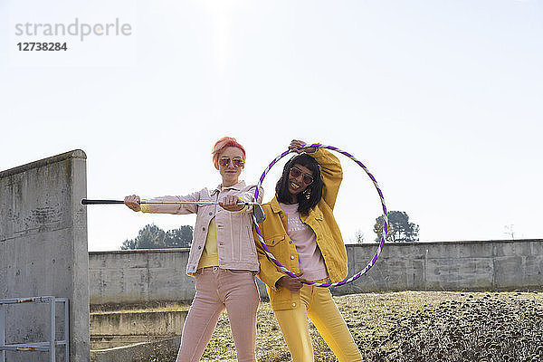 Two alternative friends holding hoola hoop and golf club