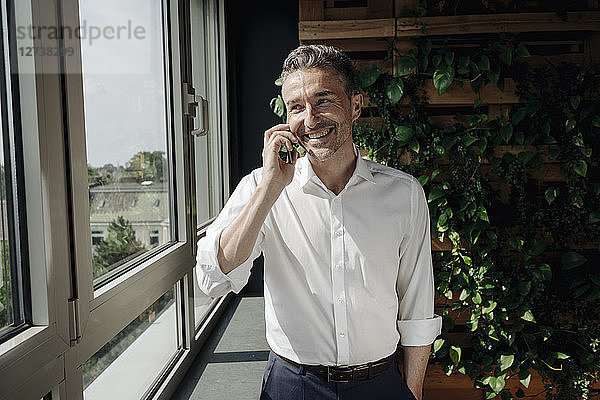 Smiling businessman on cell phone at the window