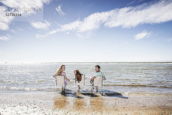 Netherlands  Zandvoort  family sitting on chairs in the sea