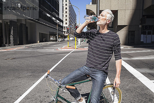 Man on bicycle drinking water