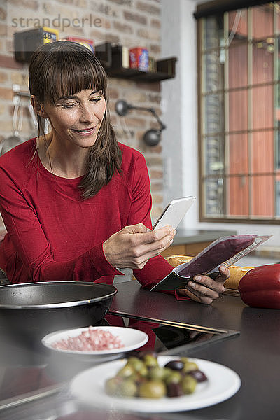 Woman in kitchen scanning products with her smartphone