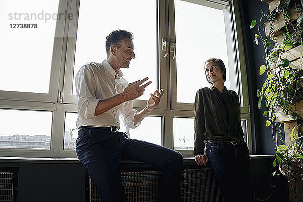 Businessman and businesswoman talking at the window