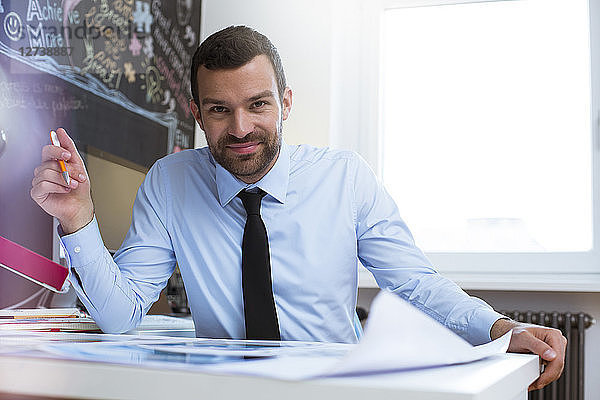 Portrait of confident businessman at desk in creative office