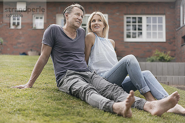 Smiling mature couple sitting in garden of their home