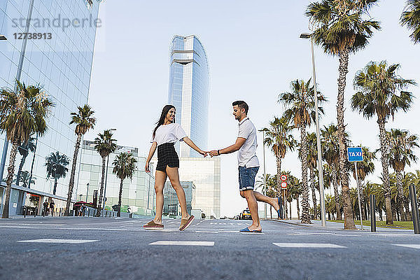 Young couple crossing street in the city  holding hands