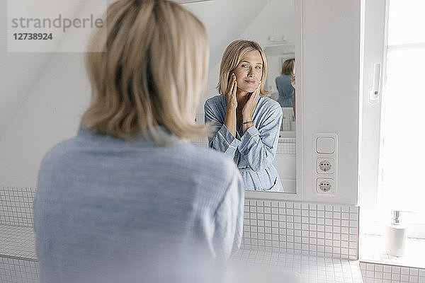 Mature woman looking in bathroom mirror