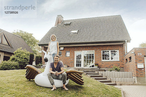 Portrait of smiling mature couple with inflatable pool toy in garden of their home