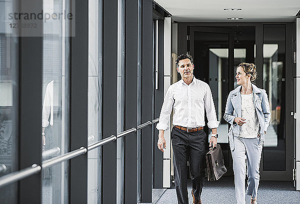 Businesswoman and businessman walking in office passageway