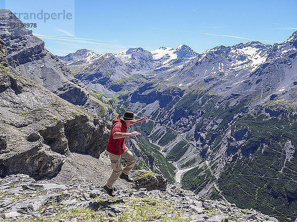 Italy  Lombardy  Sondrio  hiker jumping with view to Stelvio Pass and Ortler