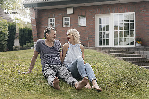 Happy mature couple sitting in garden of their home