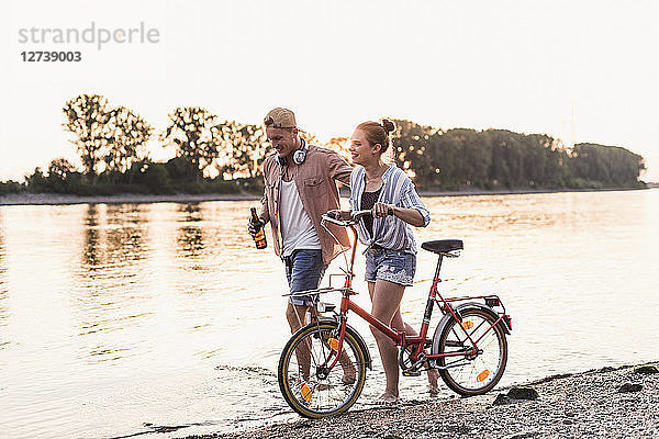 Young couple with bicycle wading in river