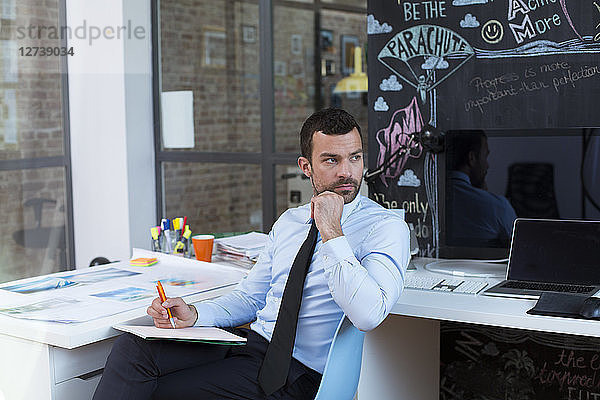 Businessman in creative office taking notes at desk