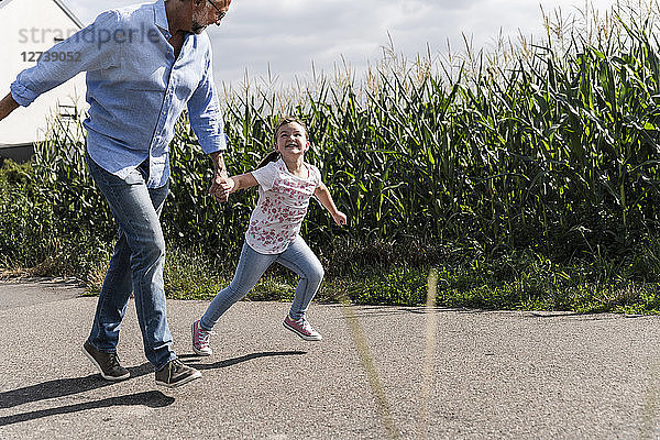 Mature man and little girl running on street  laughing