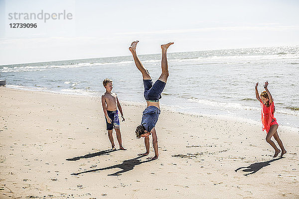 Netherlands  Zandvoort  father with two children doing a handstand on the beach
