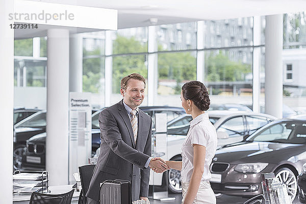 At the car dealer  Salesman and client shaking hands