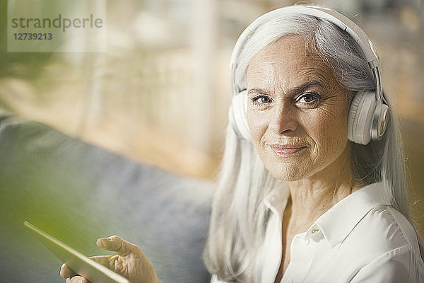 senior woman using digital tablet and headphones