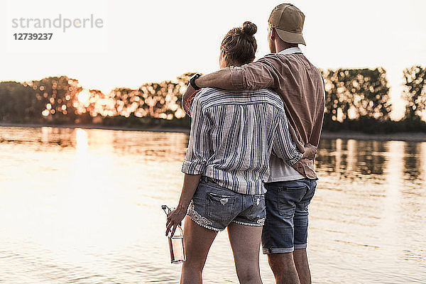 Young couple watching the sunset above a river