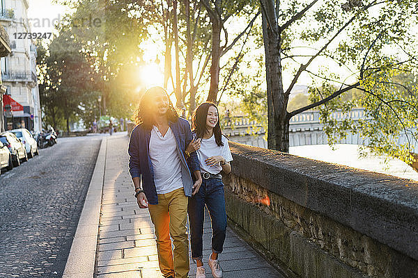 France  Paris  happy young couple walking at river Seine at sunset