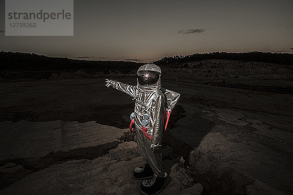 Spaceman pointing at distance at night on a nameless planet