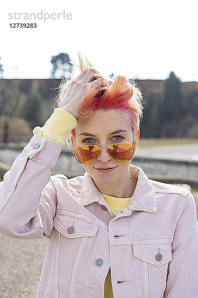 Portrait of young woman  sun glasses and pink jeans jacket