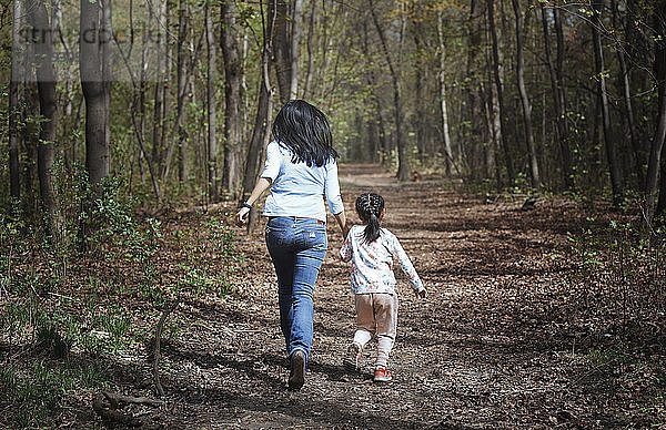 Mother and daughter running hand in hand in a park  rear view