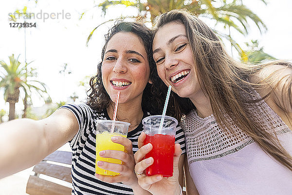 Portrait of two happy female friends enjoying a fresh slush
