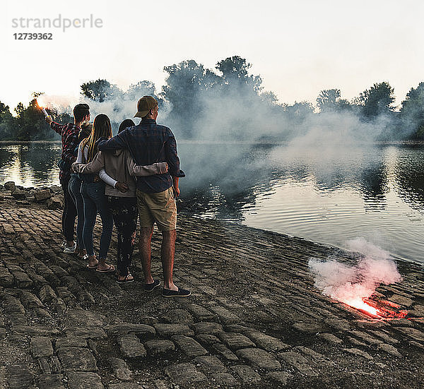 Group of friends standing at the riverside in the evening with torches