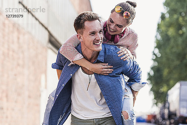 Young man giving girlfriend piggyback ride