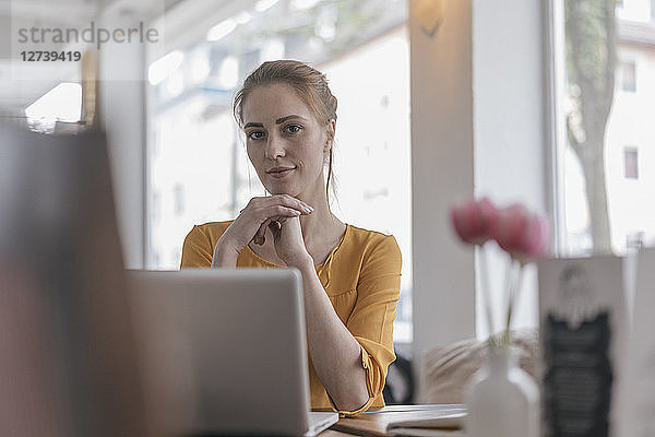 Young woman sitting in coworking space using laptop