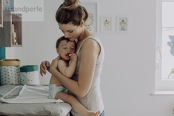 Mother changing diapers of her baby son