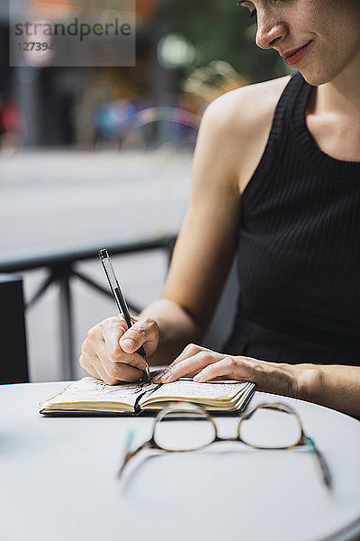Young woman sitting in coffee shop  brainstorming  writing notes in notebook