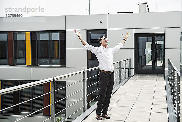 Cheering businessman standing on skywalk at office building