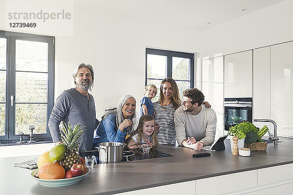 Happy family with grandparents and children standing in the kitchen