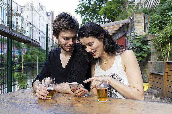 Young couple at an outdoor bar with beer and cell phone