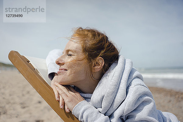 Smiling woman lying in deck chair  enjoying sunbath at the beach
