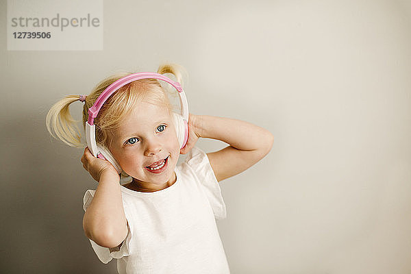 Portrait of little girl listening music with headphones dancing