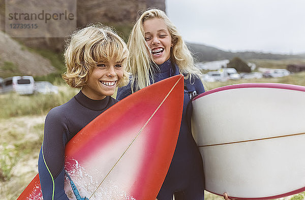 Spain  Aviles  portrait of two happy young surfers on the beach